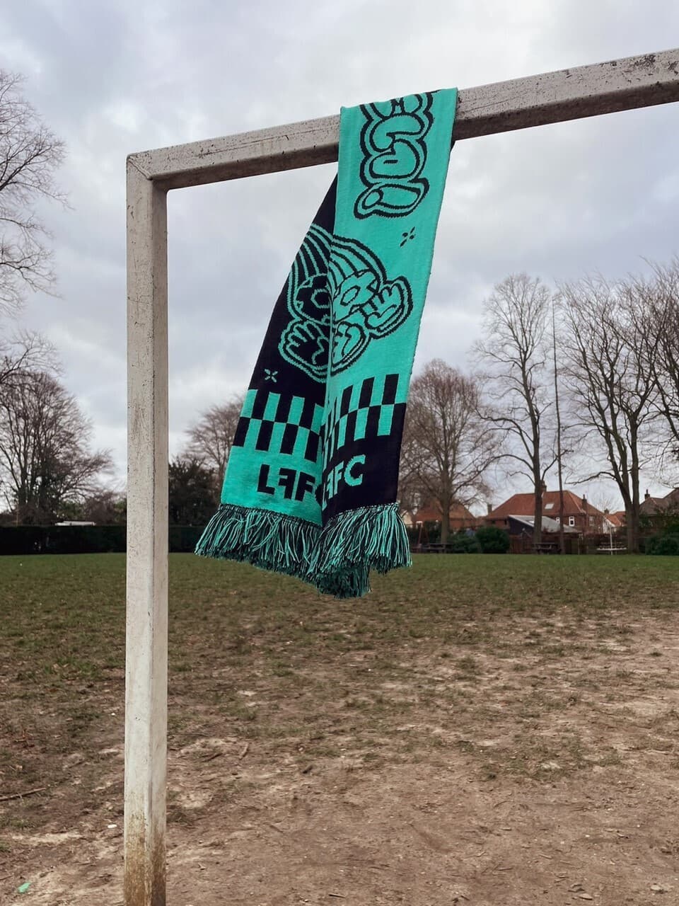 The club scarf hanging from a goal frame on a wet winter pitch