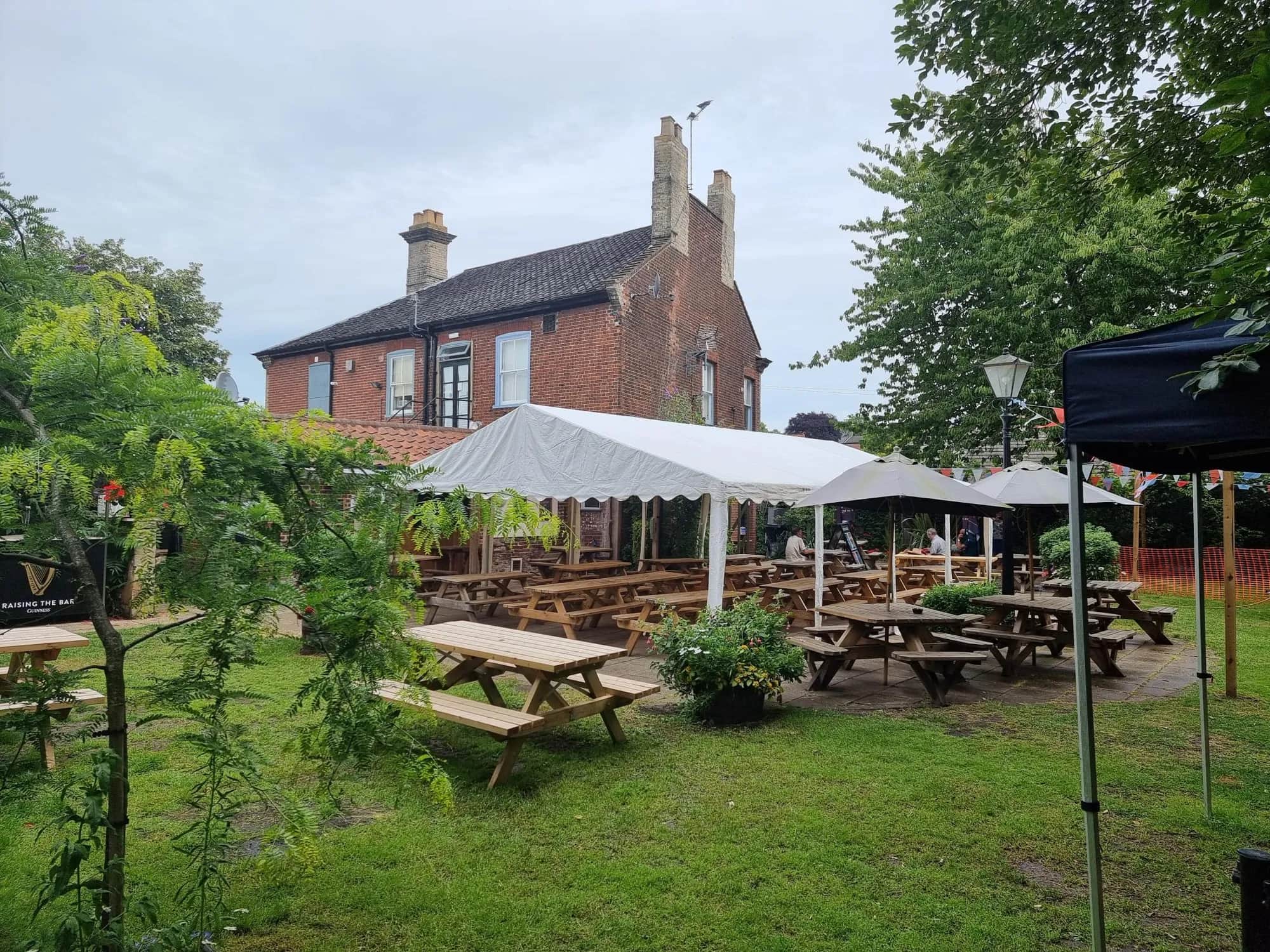 The garden at The Garden House, picnic tables under a marquee with the brick pub behind